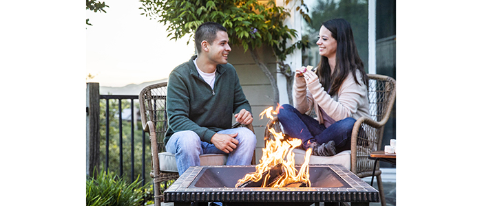 Stacked DURAFLAME® OUTDOOR FIRELOGS burning in firepit with couple smiling at each other
