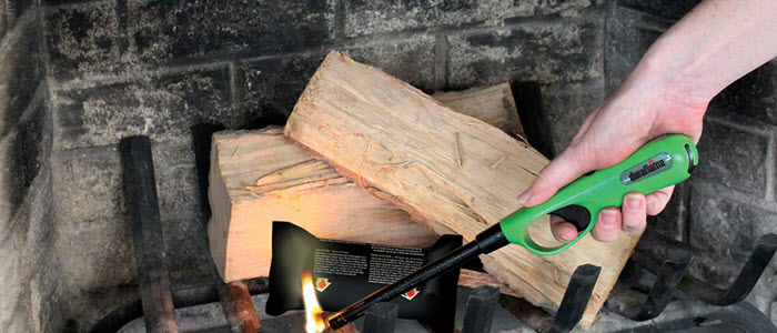 Lighter lighting a FIRESTART® GOLD FIRELIGHTER to start a wood fire in an indoor fireplace