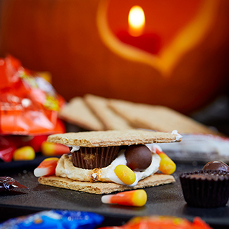Halloween themed s'mores with graham cracker, roasted marshmallow and Halloween candies
