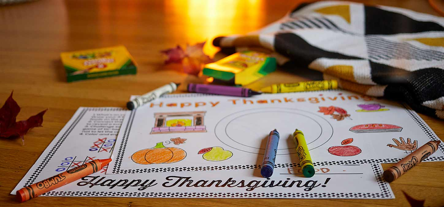 Thanksgiving coloring placements  with crayons and glow of fire on hardwood floor