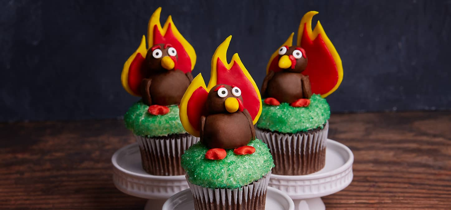 Three green cupcakes topped with fondant turkey whose plumage is in the shape of duraflame's logo flame