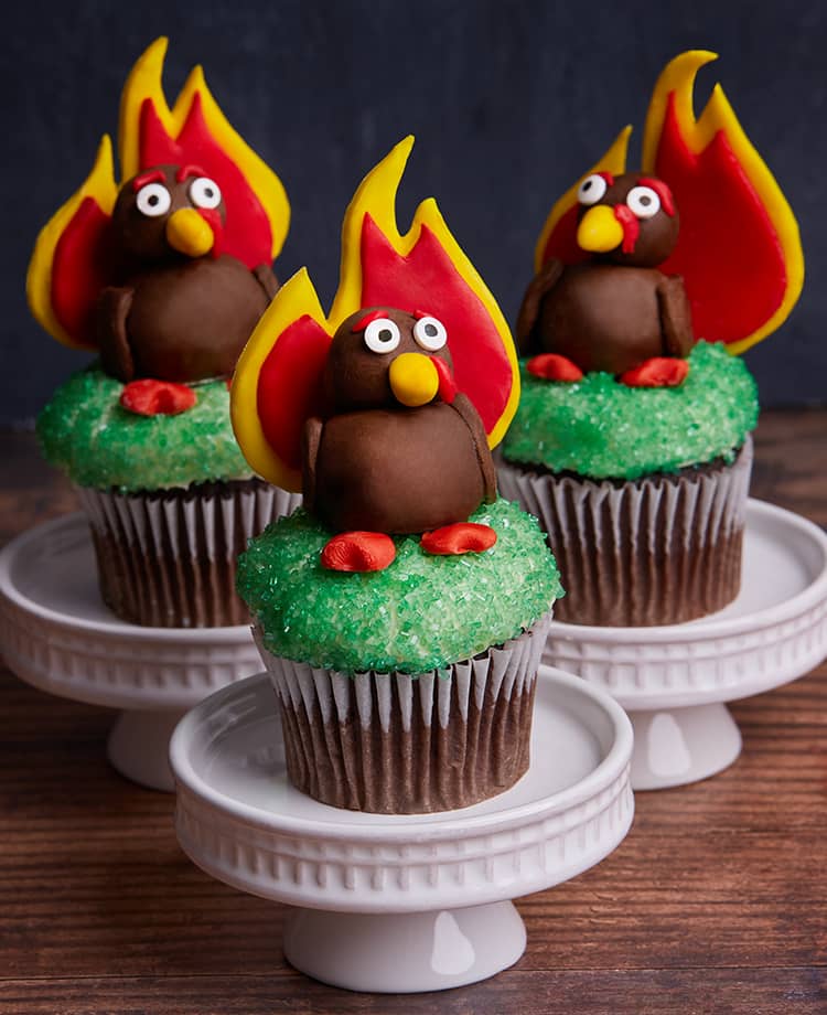 Three green cupcakes topped with fondant turkey whose plumage is in the shape of duraflame's logo flame